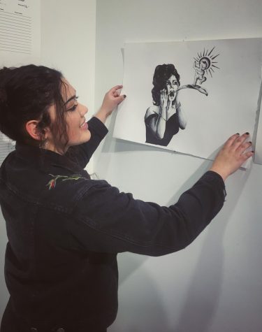 UTPB junior Sandra Vega hangs her artwork Enlightened for a recent art auction. 